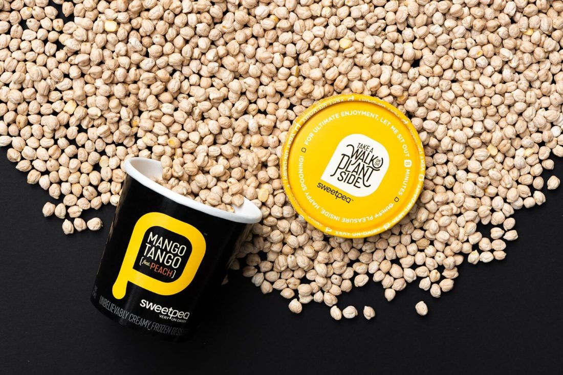 SweetPea non dairy ice cream mango tango pint open and tipped over with dry chickpeas spilling out on a black background