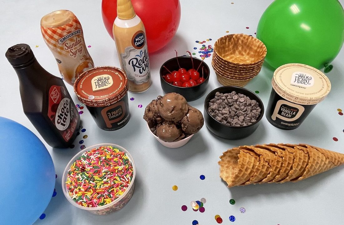 Table showing a SweetPea ice cream sundae board with sprinkles, waffle cones, and chocolate chips.