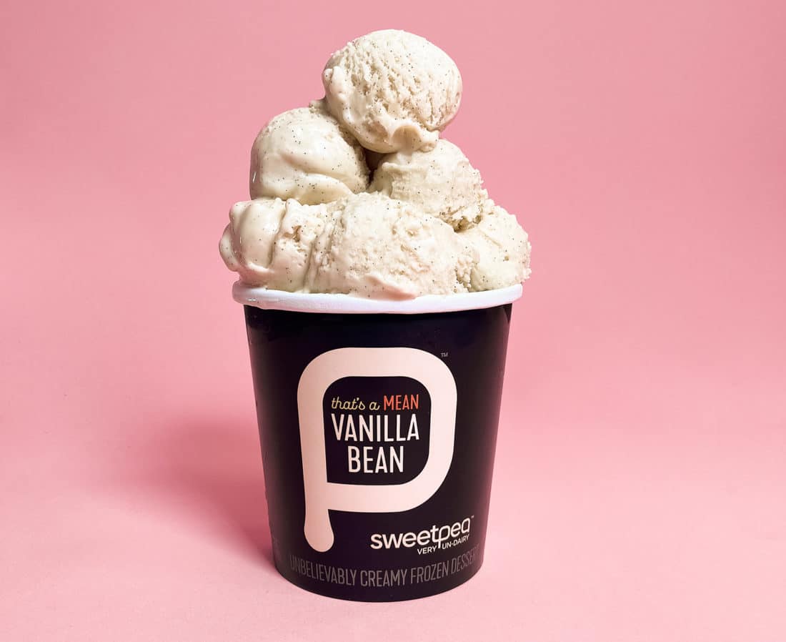 Black pint of SweetPea plant-based ice cream Thats a Mean Vanilla Bean against a light pink background.